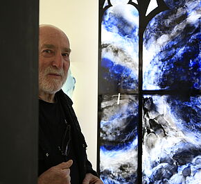 Claude baille maitre verrier devant un de ses vitraux bleu et blanc